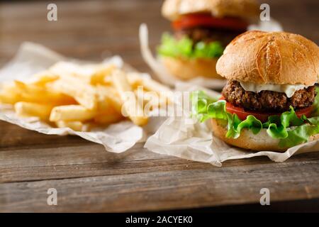 Hausgemachte leckere Burger und Pommes Frites auf Holztisch Stockfoto