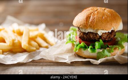 hausgemachte Burger und Pommes Frites auf einer Holzplatte Stockfoto