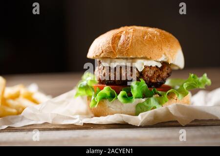 hausgemachte Burger und Pommes Frites auf einer Holzplatte Stockfoto