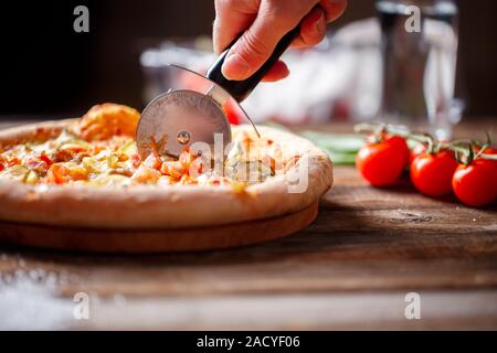 Frischen Pizza aufschneiden mit Walze Messer. Stockfoto