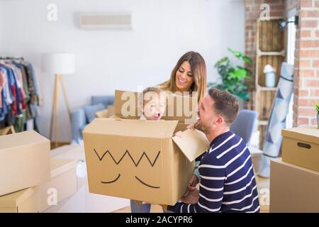Schöne famiily, Kid spielen mit seinen Eltern reiten Karton fanny Box im neuen Zuhause Stockfoto