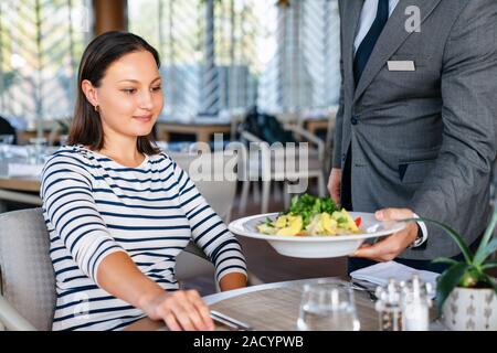 Junge Frau von Kellner für ein Mittagessen in einem elagance Restaurant serviert. Stockfoto