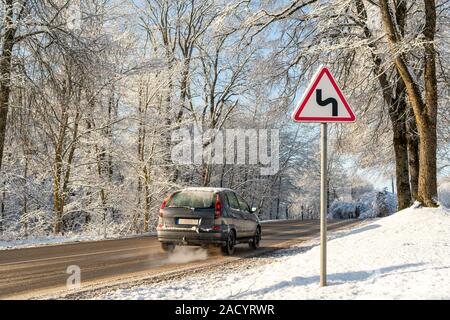 Winter Driving-Curvy Winter Straße mit Warnzeichen. Verschneite Straße im Winter, Auto auf eine gefährliche Strecke bedeckt mit Schnee und Eis. Selec Stockfoto