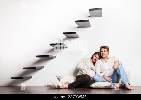 Paar zu Hause sitzen auf Treppen. Schwangerschaft Stockfoto
