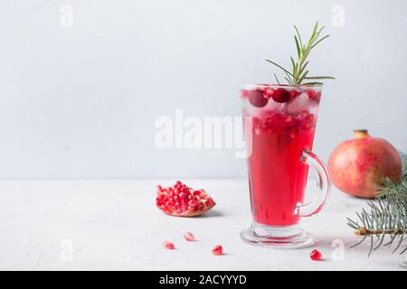 Granatapfel Weihnachten Cocktail mit Rosmarin, Champagner, club Soda auf grauem Beton Tabelle. Close Up. Stockfoto
