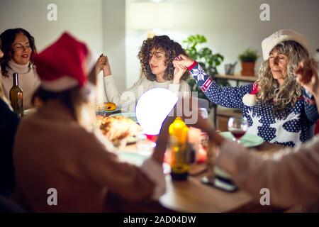 Schöne Gruppe von Frauen Lächeln glücklich und zuversichtlich. Die Hände und betet gemeinsam Weihnachten zu Hause feiern. Stockfoto