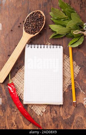 Gewürze in Löffel, Notebook auf Holz Hintergrund Stockfoto