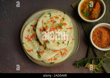 Uthappam/Oothappam - South Indian Frühstück set Dosa gekrönt mit Zwiebel Karotten mit Chutney Pulver und Sambar serviert. Stockfoto