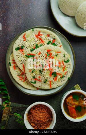 Uthappam/Oothappam - South Indian Frühstück set Dosa gekrönt mit Zwiebel Karotten mit Chutney Pulver und Sambar serviert. Stockfoto