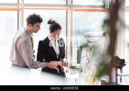 Junges Paar arbeiten auf Flip Board im Büro Stockfoto