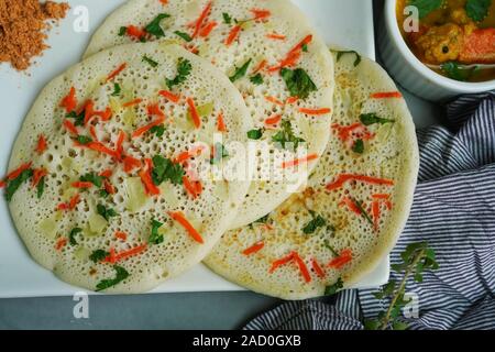 Uthappam/Oothappam - South Indian Frühstück set Dosa gekrönt mit Zwiebel Karotten mit Chutney Pulver und Sambar serviert. Stockfoto