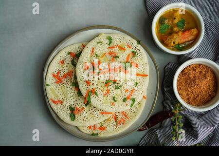 Uthappam/Oothappam - South Indian Frühstück set Dosa gekrönt mit Zwiebel Karotten mit Chutney Pulver und Sambar serviert. Stockfoto