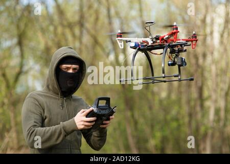 Mann mit Maske, die eine Drohne mit Fernbedienung in Betrieb. Stockfoto