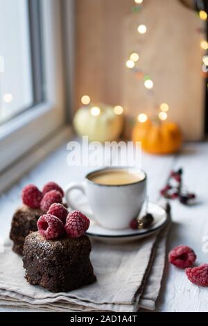 Dessert Schokolade auf der Fensterbank mit Himbeeren und leckeren Kaffee. Weihnachtsdekorationen. Gesundes Essen und Trinken Stockfoto