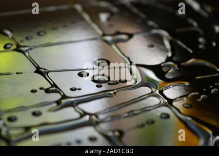 Wasser und Öl Tröpfchen in der Form der Kunst Inschriften auf einem schwarzen Oberfläche aus Metall mit Lichtreflexen. Ungewöhnlich abstrakten Hintergrund, Kunst und Licht. Stockfoto