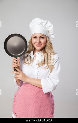 Schöne, junge blonde Frau mit Pfanne Stockfoto