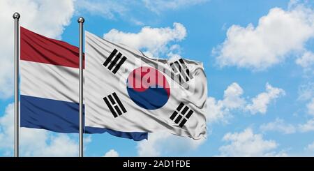 Niederlande und Südkorea Flagge im Wind gegen Weiße bewölkt blauer Himmel zusammen. Diplomatie Konzept, internationale Beziehungen. Stockfoto