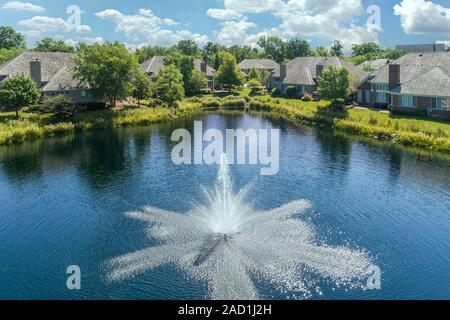 Luftaufnahme von einer Hotelanlage im Stadthausstil mit einem Teich und Brunnen in einem Chicago Vorstadtnachbarschaft im Sommer. Stockfoto