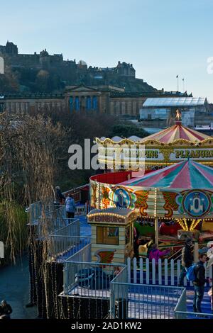 Das Edinburgh Castle, Weihnachtsmarkt und Fair. Karussell und Markt im Vordergrund. Schottland Stockfoto