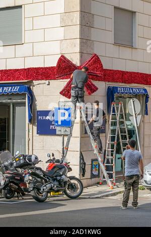 Civitavecchia, Italien - 30. Oktober 2019: Einheimische ihre Straße und Kondominium Largo Plebiscito Nr. 4 Dekoration für Weihnachten mit einem riesigen Ribbon Stockfoto