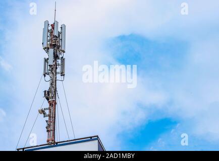 Mobile Station und Antenne auf dem Dach eines Gebäudes mit Himmel und Wolken im Hintergrund Stockfoto