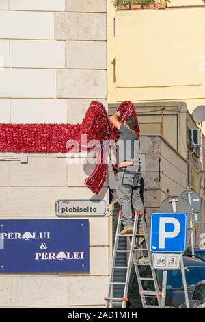 Civitavecchia, Italien - 30. Oktober 2019: Einheimische ihre Straße und Kondominium Largo Plebiscito Nr. 4 Dekoration für Weihnachten mit einem riesigen Ribbon Stockfoto