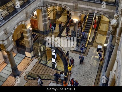 Amsterdam, Holland, August 201. Blick von der Lobby der Magna Plaza, luxuriöse Einkaufszentrum der Stadt. Menschen gehen, die Treppe von einer Fl zu bewegen Stockfoto