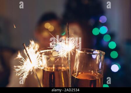 Weihnachten und Neujahr party Konzept. Verliebtes Paar brennende Wunderkerzen beleuchtete Weihnachtsbaum mit Champagner. Stockfoto