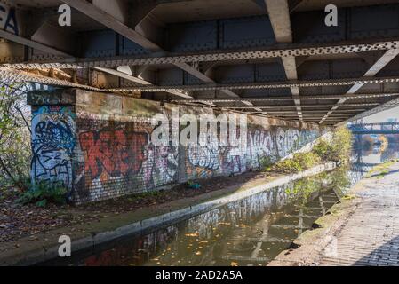 Graffiti malte auf eine Mauer durch eine Brücke über die Worcester und Birmingham Canal in Selly Oak, Birmingham, Großbritannien Stockfoto