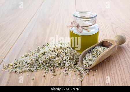 Hanf Öl in einem Glas und Hanf Samen in einem Löffel aus Holz Stockfoto