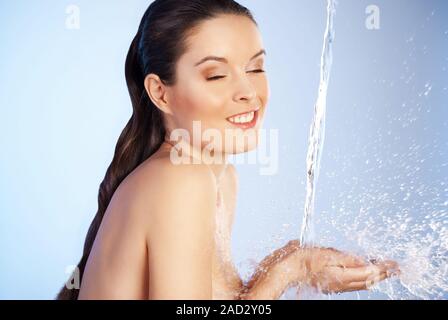 junge schöne Frau unter dem Strahl des Wassers Stockfoto