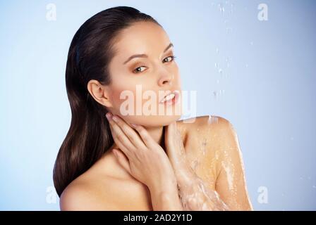 junge schöne Frau unter dem Strahl des Wassers Stockfoto