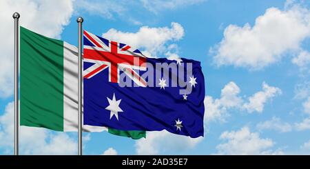 Nigeria und Australien Flagge im Wind gegen Weiße bewölkt blauer Himmel zusammen. Diplomatie Konzept, internationale Beziehungen. Stockfoto