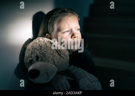 Trauriges kleines Mädchen umarmt ihren Teddy Bär - fühlt sich einsam Stockfoto