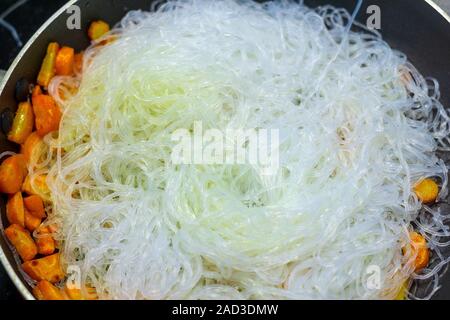 Glasnudeln Zellophan Nahaufnahme in der Pfanne. Hintergrund Nudeln kochen, braten Gemüse Stockfoto