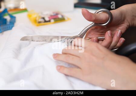 Schneiderin schneidet Tuch paar Schere Stockfoto