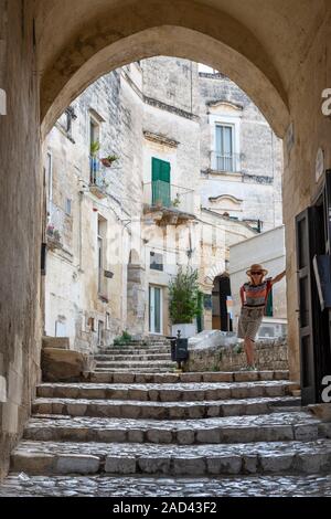 Frau unter arch auf Rione Vetera, einem schmalen Weg von der Kathedrale in der Sassi von Matera, Basilikata, Süditalien führenden Posing Stockfoto