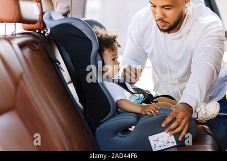 Junge Eltern anpassen Kindersitz für seinen kleinen Sohn Stockfoto