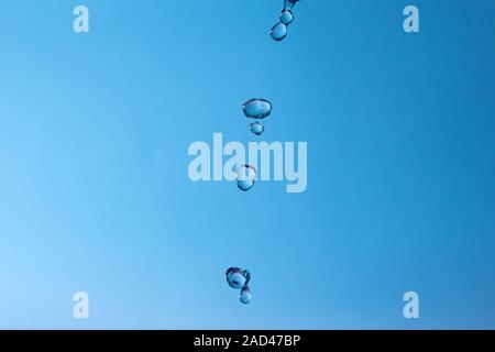 Fallende Wassertropfen auf einem blauen Hintergrund. Stockfoto