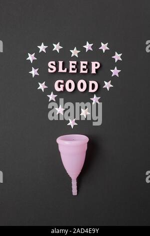 Rosa Menstruationsschale auf schwarzen Hintergrund mit mit Herz und Worte gut Schlafen. Konzept Einsatzmöglichkeit Cup in der Nacht, null Abfall, Einsparungen, Minimalismus. Stockfoto
