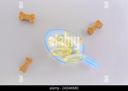 Omega capseln für Tiere und Haustiere in einem Löffel und behandelt auf grauem Hintergrund Stockfoto