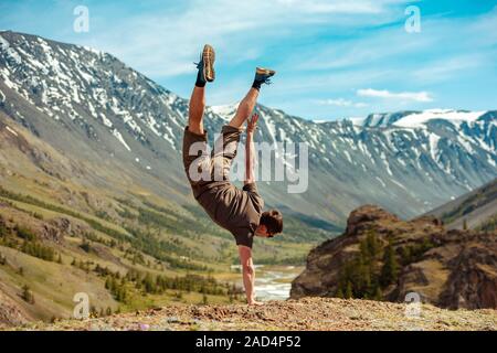 Starke Mann macht akrobatische Tricks und stehend auf der Hand auf den Kopf Stockfoto