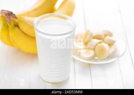 Joghurt mit frischen Bananen auf weißem Holz Hintergrund Closeup, gesundes Frühstück Stockfoto