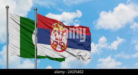 Pakistan und Serbien Flagge im Wind gegen Weiße bewölkt blauer Himmel zusammen. Diplomatie Konzept, internationale Beziehungen. Stockfoto