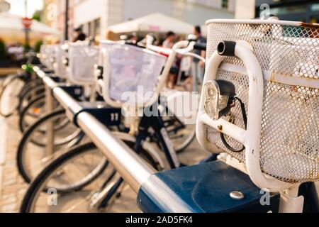 Zeile der geparkten vintage Fahrräder Fahrräder zu mieten auf dem Bürgersteig. Fahrrad Parken in der europäischen Stadt. In der Nähe von Rad, Rusty Baske Stockfoto