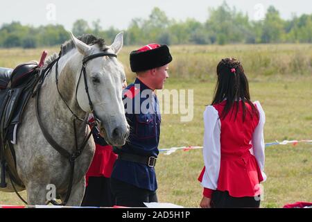 Samara, Russland - Oktober 07, 2019: Junge Kosak Kosak und Mädchen in Trachten steht neben dem Pferd. Das Mädchen sagt Auf Wiedersehen zu den Cossac Stockfoto