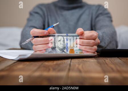 Kaukasische Hände zählen-Dollar-Banknoten auf dunklen Holztisch Stockfoto