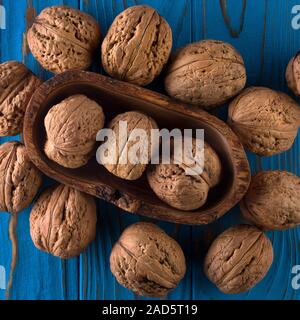 Ansicht von oben Foto von ganze Walnüsse auf Blau lackiert Holztisch in der Schüssel Stockfoto