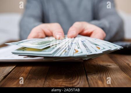 Kaukasische Hände zählen-Dollar-Banknoten auf dunklen Holztisch Stockfoto