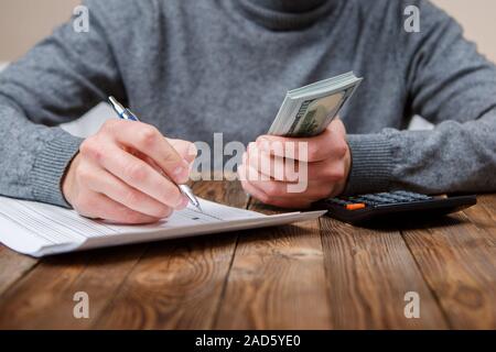 Kaukasische Hände zählen-Dollar-Banknoten auf dunklen Holztisch Stockfoto